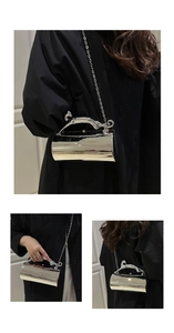Detail of silver cylindrical evening bag featuring a leopard-shaped metal handle and chain