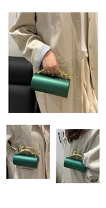 Detail of emerald cylindrical evening bag featuring golden leopard handle and chain strap