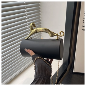 Detail of the golden leopard handle on a matte black cylinder evening bag with chain
