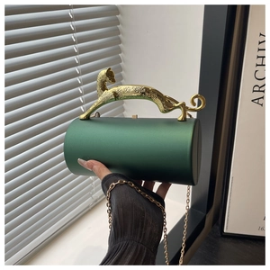 Detail of green cylindrical evening bag featuring a golden leopard handle and metal chain
