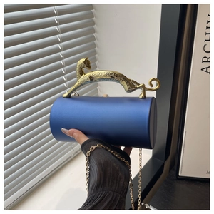 Detail of royal blue cylindrical evening clutch with a gold leopard-shaped handle