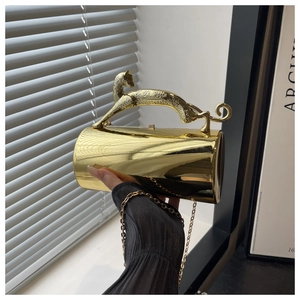 Detail of gold cylindrical evening bag with panther-shaped handle and metal chain