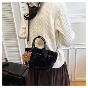 Detail of black faux fur plush handbag with leather handles and bird charm on a model