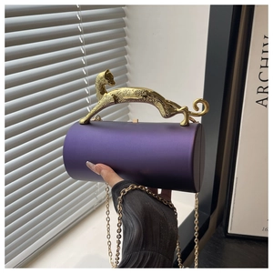 Detail of purple cylindrical clutch bag featuring a gold leopard-shaped metal handle