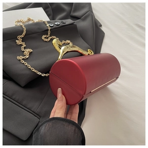 Detailed macro of burgundy cylindrical clutch featuring a golden leopard-shaped handle