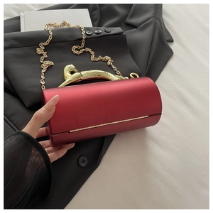 Close-up of red cylindrical clutch bag with iconic gold leopard handle and chain