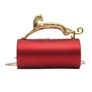 Macro shot of red cylindrical acrylic evening bag with a gold leopard handle and chain