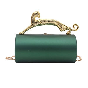 Detail of green cylinder clutch featuring a golden leopard handle and metal chain
