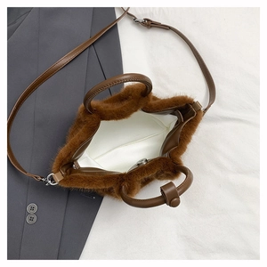 Detailed top view of a brown plush handbag with leather straps on a grey suit background