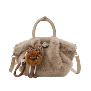 Bruine handtas van pluizig imitatiebont met beige handvat en pluche hanger op witte achtergrond