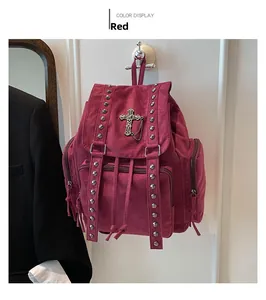 Detailansicht eines dunkelroten Rucksacks mit gotischem Kreuzanhänger und Metallnieten