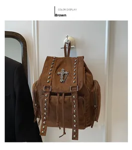 Nahaufnahme der braunen Wildledertasche mit silbernen Nieten und großem Metallkreuz
