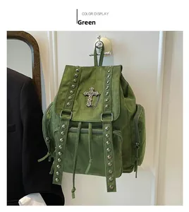 Detail eines grünen Wildlederrucksacks mit Metallnieten und Gothic-Kreuz-Anhänger