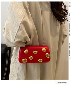 Elegant red evening clutch with gold pebble-like metal details and chain strap