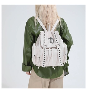 Detailaufnahme des beigen Canvas-Rucksacks mit Nieten und gotischem Kreuz auf dem Model