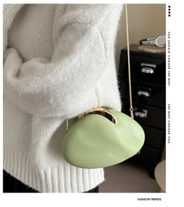 Close-up of light green pebble-shaped PU clutch bag with golden metallic clasp