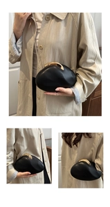 Close-up of pebble-shaped black leather evening clutch bag with golden metal buckle and chain