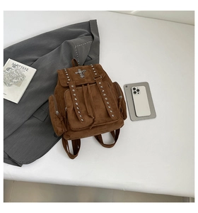 Flachbild des braunen Wildlederrucksacks mit Nieten und Kreuzlogo auf weißem Hintergrund