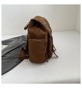 Detailansicht eines braunen Wildlederrucksacks mit Metallnieten und modischen Fransen