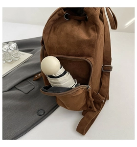 Detailansicht der vorderen Reißverschlusstasche eines braunen Wildlederrucksacks mit Schirm