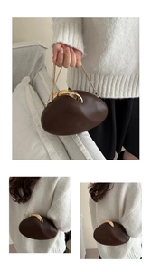 Detail of a brown pebble-shaped clutch bag with gold clasp and fine chain strap