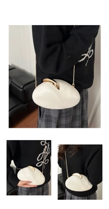 Detail of white pebble shaped clutch bag with golden metal clasp and chain strap