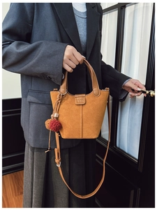 Borsa a secchiello marrone scamosciata con charm a pompon e giacca grigio scuro