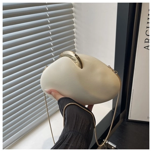 Detail of egg-shaped cream PU clutch with golden handle and fine metal chain strap