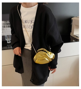 Close-up of golden irregular streamline metal evening bag with glossy mirror finish and chain