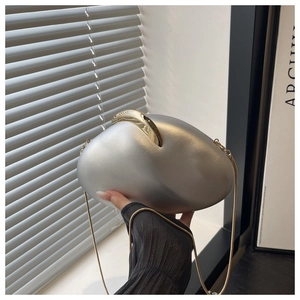 Silver pebble-shaped clutch bag with gold clasp and chain strap held by a model