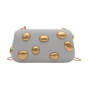 Detail of light gray clutch featuring unique gold pebble accents and a sleek snake chain
