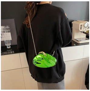 Glossy green acrylic evening bag with gold chain strap shown in a modern bar setting