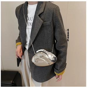 Mirror silver acrylic clutch bag with metal chain strap worn on a gray suit jacket