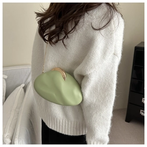 Close-up of light green pebble-textured shoulder bag with gold metal chain strap