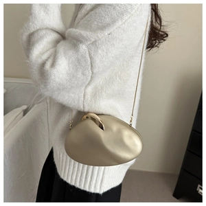 Detail of champagne gold pebble-shaped evening clutch bag with fine gold chain strap