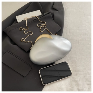 Silver hard shell evening clutch bag shown next to a smartphone for size reference