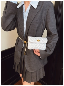 Detailansicht einer weißen gesteppten Gürteltasche mit Goldverschluss und eleganter Kette