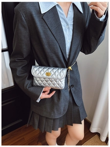 Silberne Stepp-Gürteltasche mit goldener Kette und Kugelverschluss über grauem Blazer