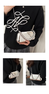 Detail view of silver acrylic evening bag with beaded handle and metal chain strap