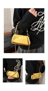 Detail of mirrored gold evening clutch featuring a beaded handle and fine metal chain strap