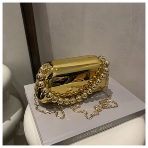 Detail of golden acrylic clutch bag with a pearl bead handle and fine metal chain strap