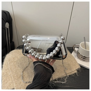 Macro shot of silver mirrored clutch bag featuring chunky beaded handle and metal chain strap