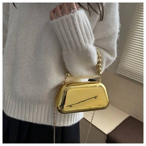 Detail of a luxury gold acrylic evening clutch with beaded handle and metal chain strap