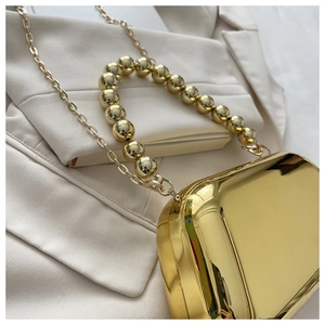 Macro detail of gold plating evening clutch with large bead handle and chain strap