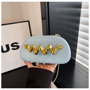 Detail of light blue leather clutch featuring a wavy gold metal accent and chain strap
