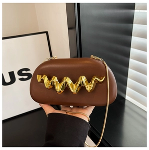 Detail of brown faux leather clutch with elegant gold wavy hardware and chain strap