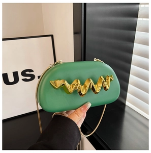 Close-up of green capsule clutch bag with gold wave decor and metallic chain strap