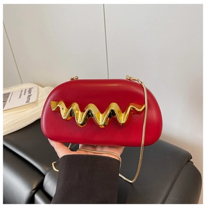 Detail of red clutch bag with golden wavy metal piece and elegant snake chain strap