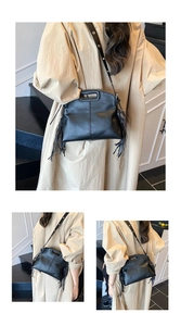Detail view of a black PU leather tote bag with long side tassels and cutout handle