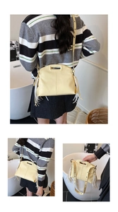 Detail view of yellow PU leather tote featuring decorative white tassels and a wide strap